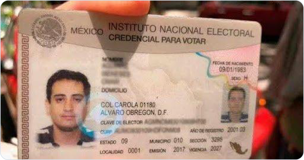 INE credential photographed at an angle, holographic glare and wear obscuring data fields.